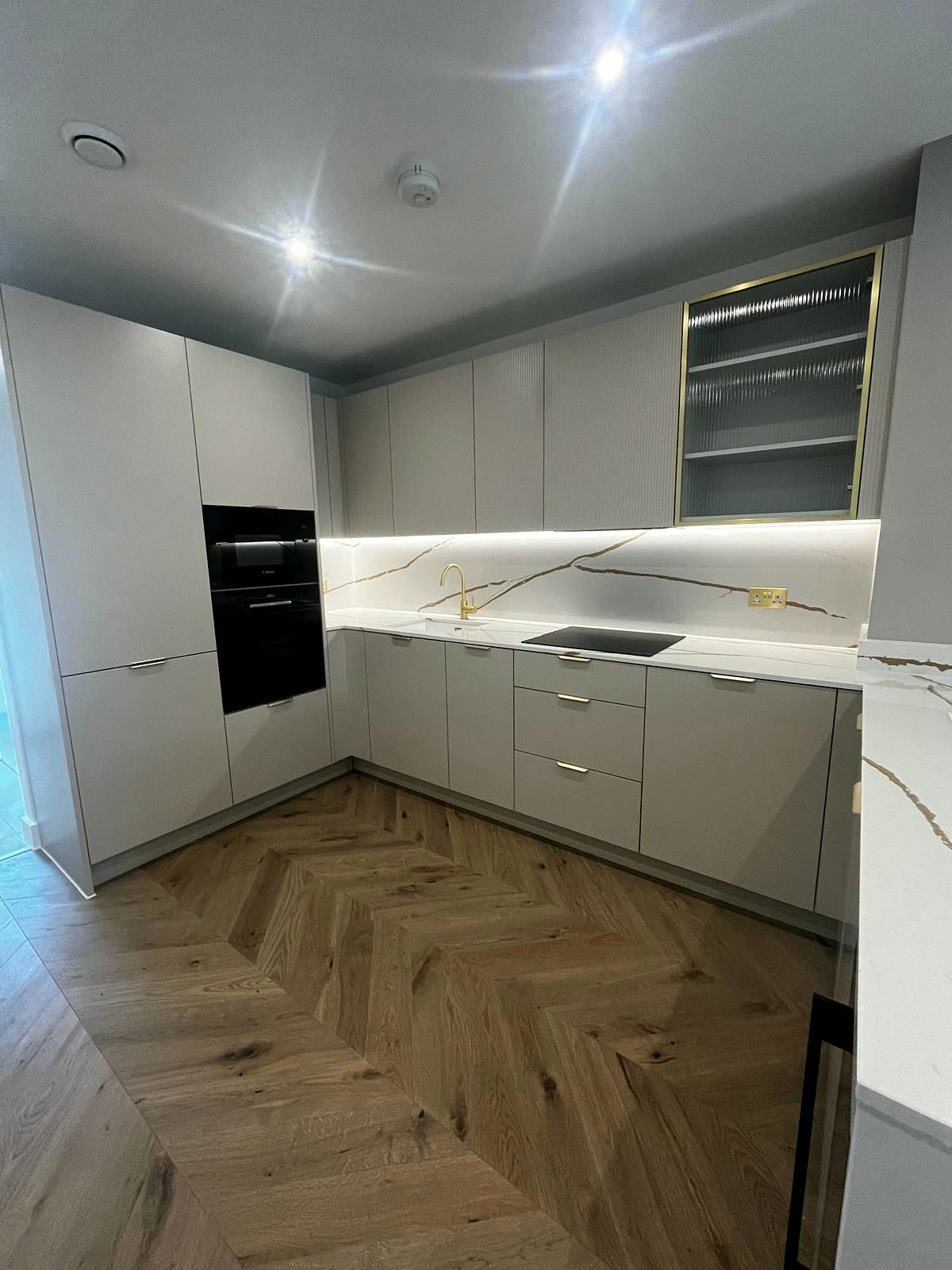 Handleless kitchen with marble-effect worktop and herringbone floor