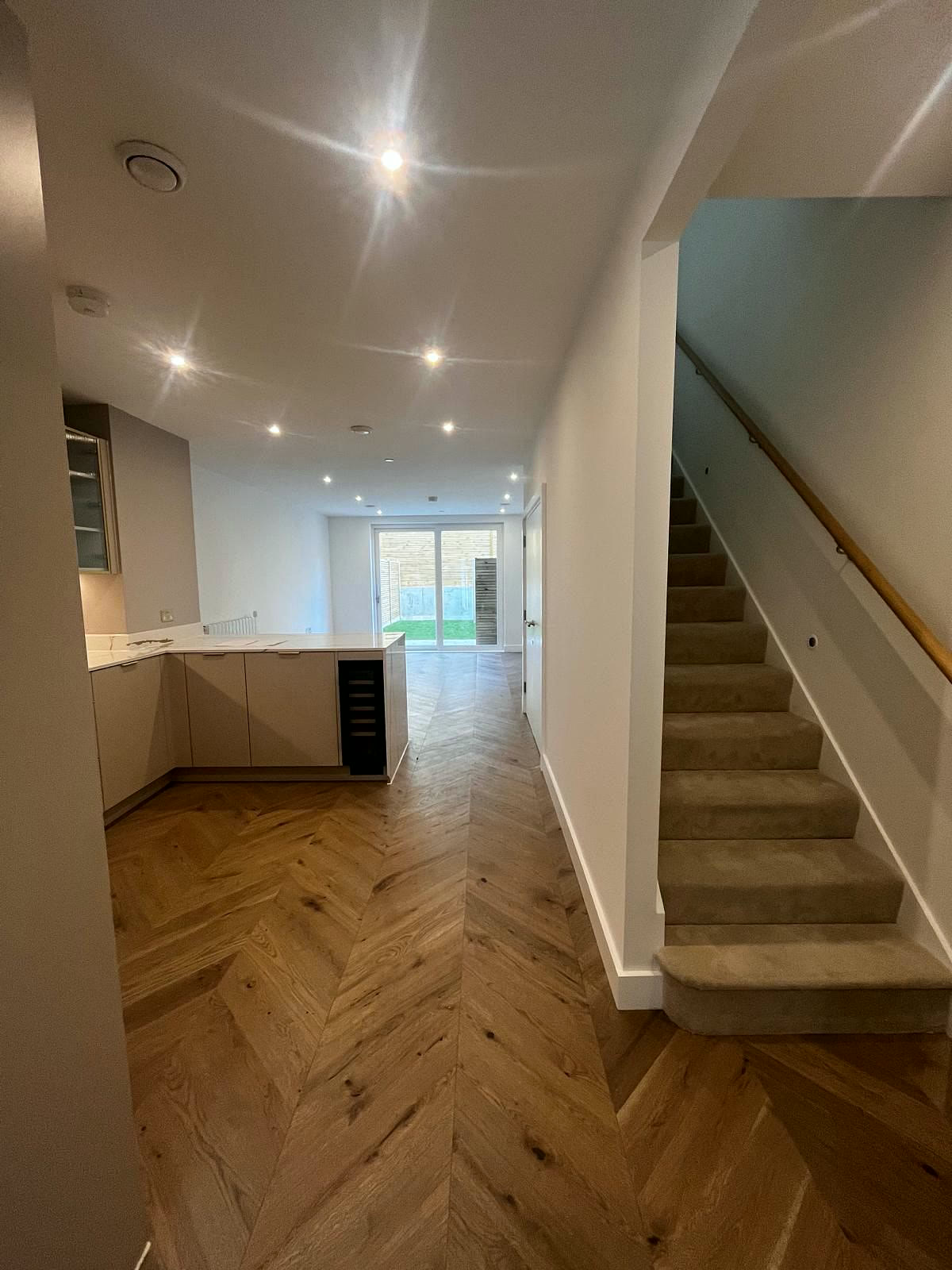 Open-plan ground floor with herringbone floor and staircase