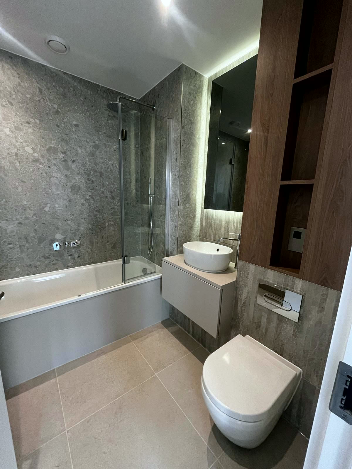 Bathroom with stone-effect tiles, bath and wall-hung WC