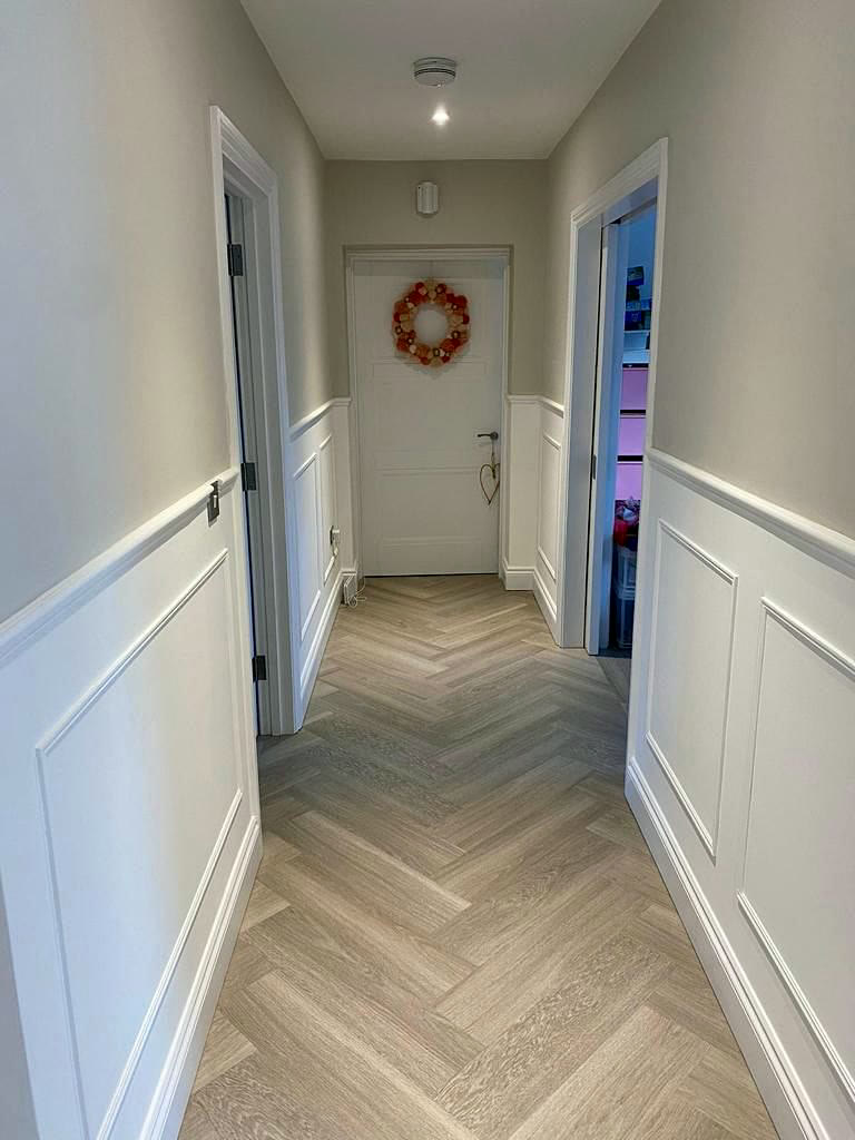 Hallway with half-height panelling and oak herringbone floor